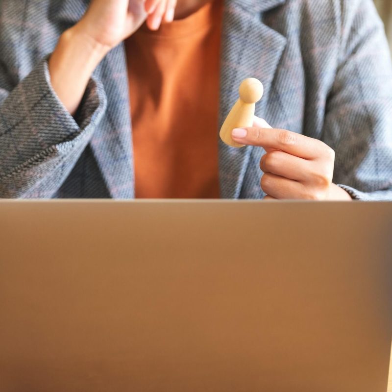 businesswoman-leader-holding-and-choosing-wooden-people-while-working-on-laptop-computer-in-office.jpg